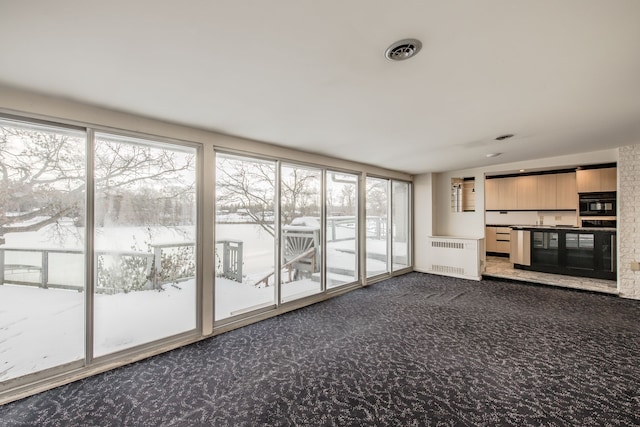 unfurnished living room with dark colored carpet and radiator heating unit