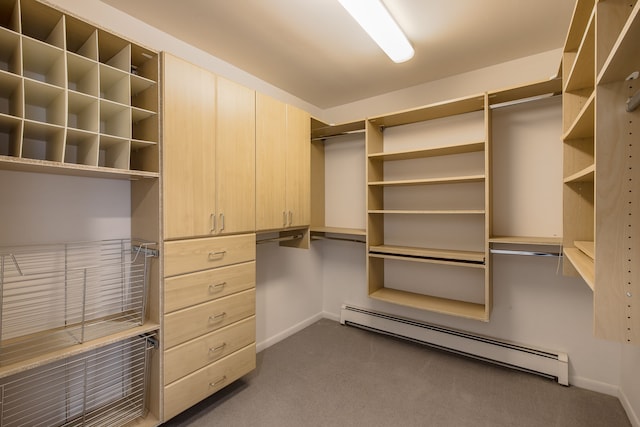 spacious closet with dark colored carpet and a baseboard radiator