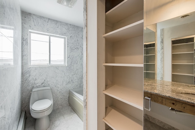 bathroom with a washtub, vanity, tile walls, and toilet