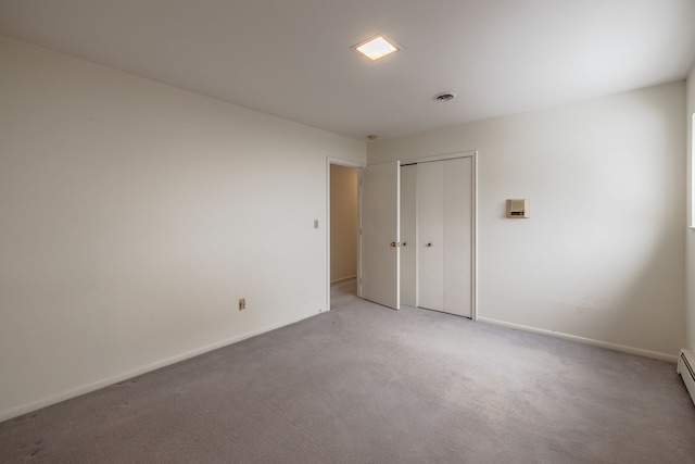 unfurnished room featuring baseboard heating and light carpet