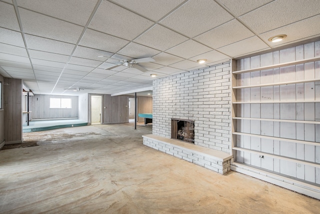 unfurnished living room with a fireplace, ceiling fan, and a drop ceiling