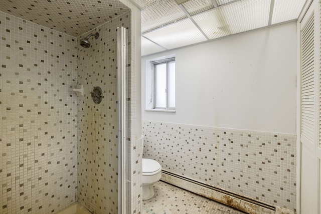 bathroom featuring a shower, tile patterned flooring, tile walls, and toilet