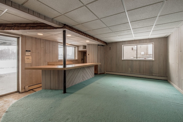 basement with carpet, a drop ceiling, and baseboard heating