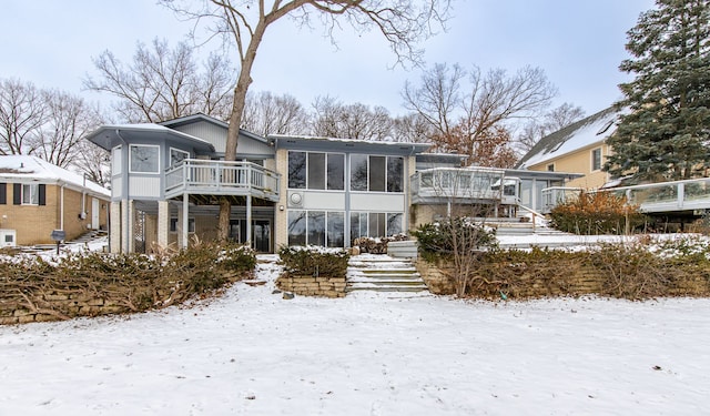 snow covered property with a sunroom and a deck