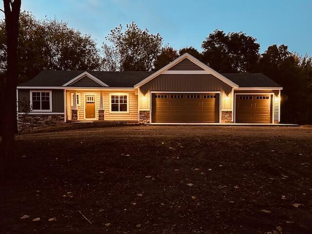 view of front of property featuring a garage, stone siding, and board and batten siding