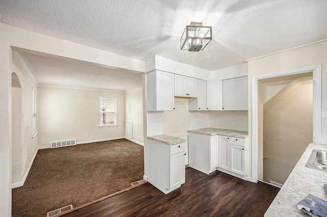 kitchen featuring white cabinets, sink, light stone countertops, and dark wood-type flooring