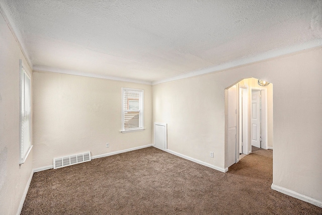 empty room with carpet flooring, a textured ceiling, and ornamental molding