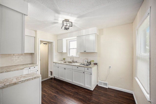 kitchen with dark hardwood / wood-style flooring, backsplash, white cabinetry, and sink