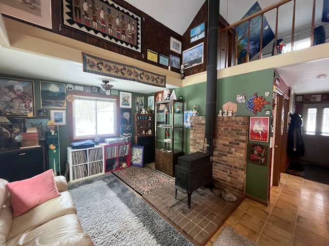 living room featuring tile patterned flooring, lofted ceiling, and a wood stove