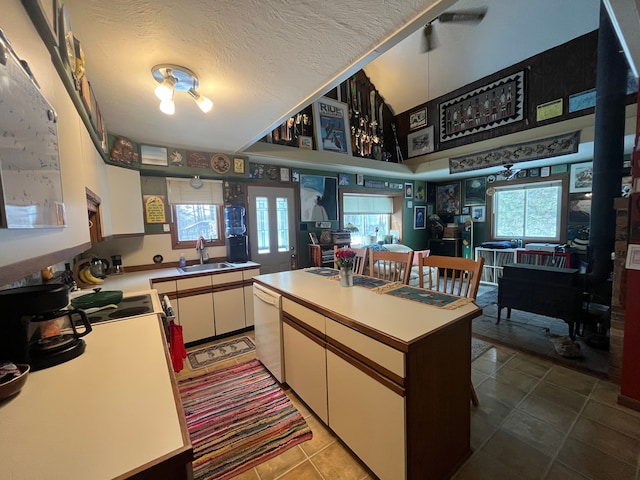 kitchen with a textured ceiling, a center island, white cabinetry, white dishwasher, and sink