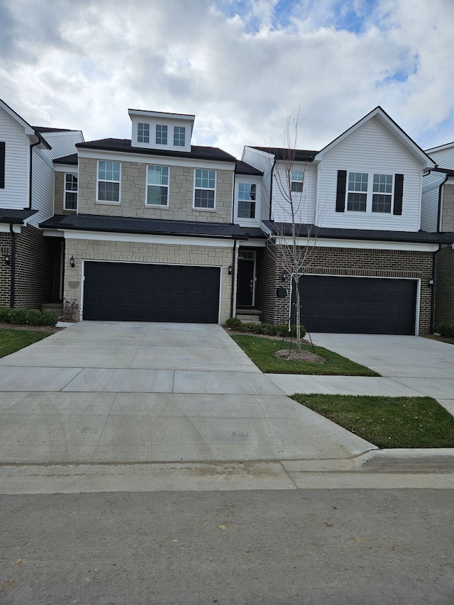 view of front of house with a garage, concrete driveway, brick siding, and stone siding