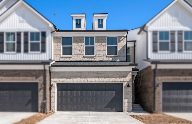 multi unit property featuring an attached garage, driveway, and stone siding