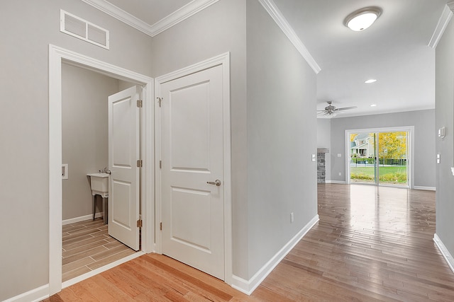 hallway featuring crown molding and light hardwood / wood-style flooring