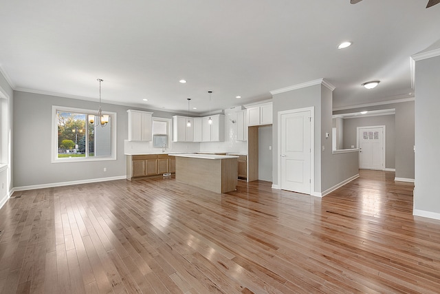 kitchen featuring a center island, decorative light fixtures, white cabinetry, and crown molding