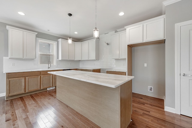 kitchen with white cabinetry, a center island, and ornamental molding