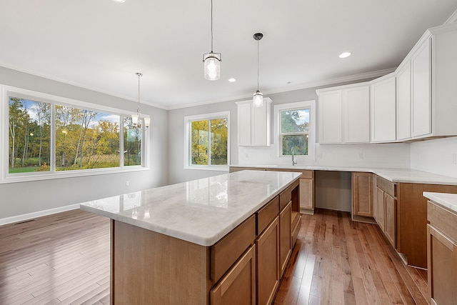 kitchen featuring a healthy amount of sunlight, a kitchen island, white cabinetry, and hanging light fixtures