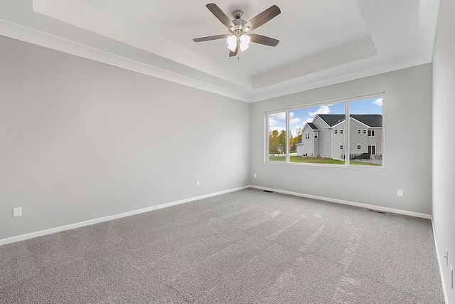 carpeted spare room featuring a raised ceiling and ceiling fan