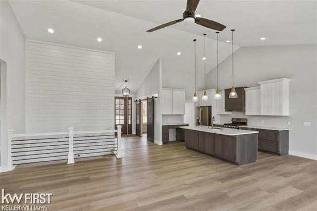 kitchen featuring pendant lighting, a center island with sink, white cabinets, ceiling fan, and appliances with stainless steel finishes