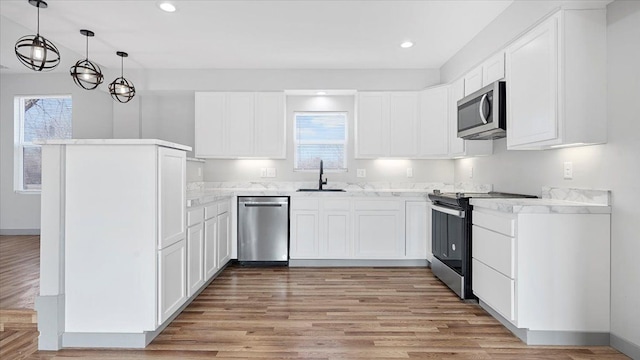 kitchen featuring sink, white cabinetry, hanging light fixtures, stainless steel appliances, and a healthy amount of sunlight