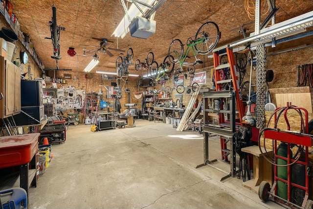 garage featuring a workshop area, a garage door opener, and ceiling fan