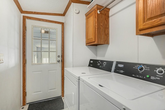 laundry room with a textured ceiling, cabinets, crown molding, and washing machine and dryer