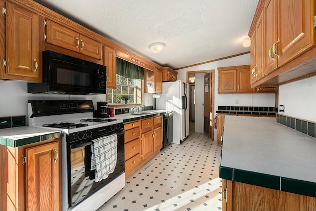 kitchen with a textured ceiling, vaulted ceiling, crown molding, and black appliances