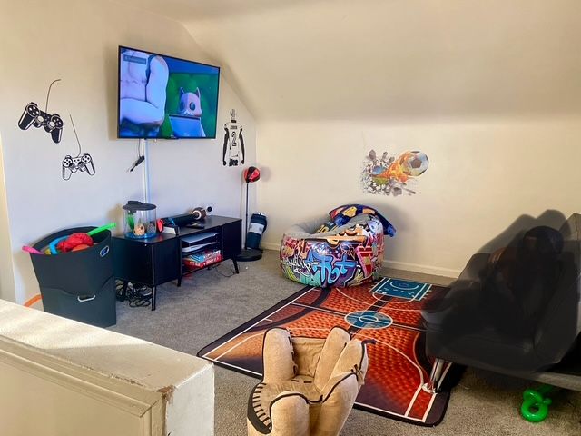 rec room with carpet and lofted ceiling