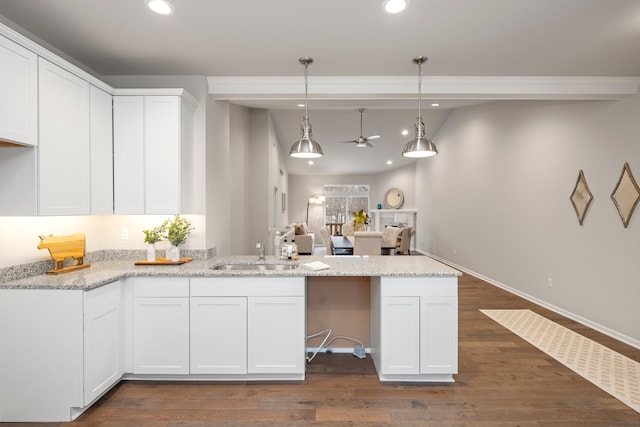 kitchen with decorative light fixtures, white cabinetry, and sink