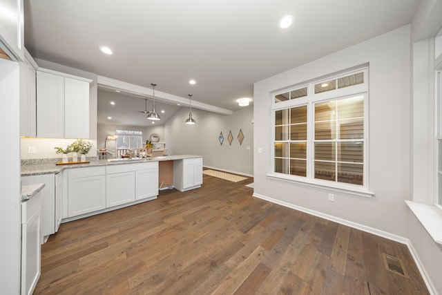 kitchen with light stone countertops, kitchen peninsula, dark hardwood / wood-style flooring, decorative light fixtures, and white cabinetry