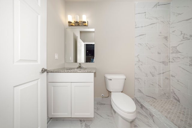 bathroom featuring tiled shower, vanity, and toilet