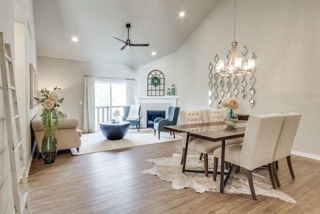 dining room with light hardwood / wood-style floors, high vaulted ceiling, and ceiling fan