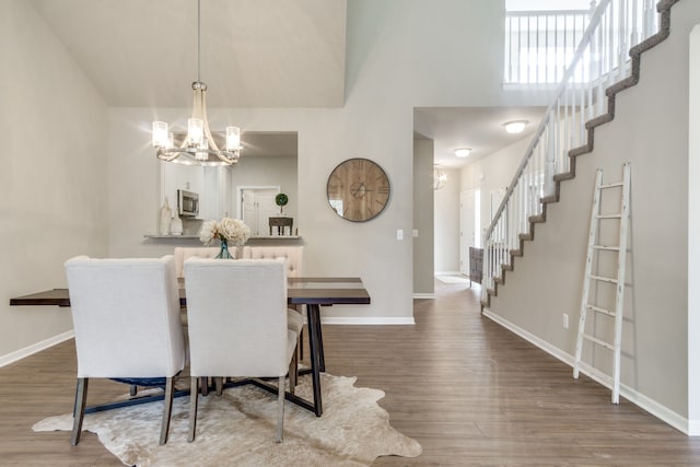 dining room featuring dark hardwood / wood-style floors, a towering ceiling, and an inviting chandelier