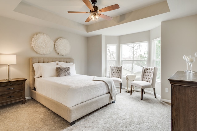 carpeted bedroom with a tray ceiling and ceiling fan