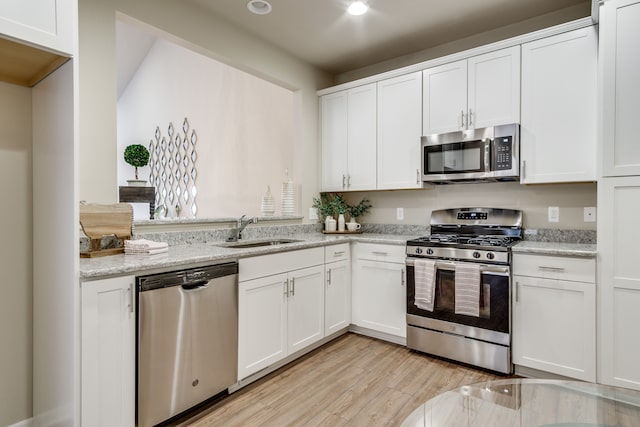 kitchen with white cabinets, light stone counters, sink, and stainless steel appliances