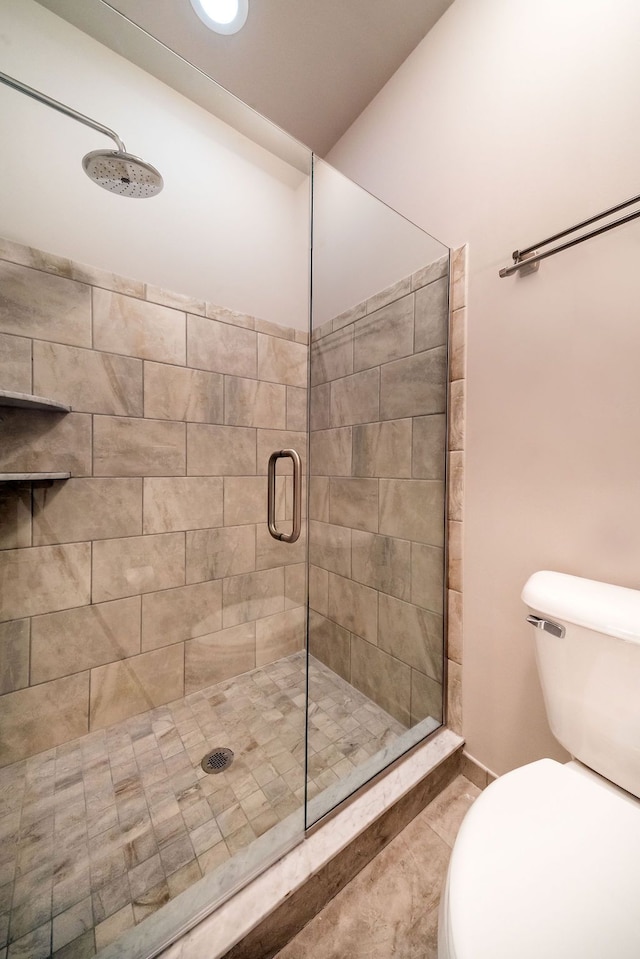 bathroom with toilet and a shower with shower door