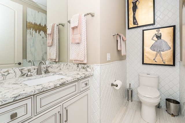 bathroom with tile walls, toilet, tile patterned floors, and vanity