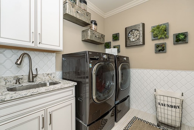 clothes washing area featuring cabinets, ornamental molding, washer and clothes dryer, and sink