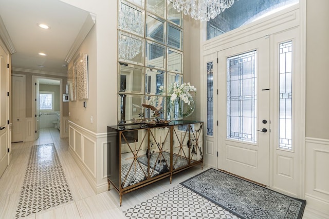 foyer entrance with light tile patterned flooring, a notable chandelier, and crown molding