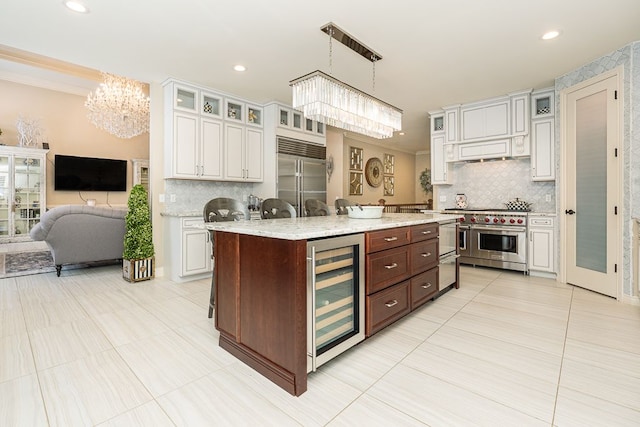 kitchen with decorative light fixtures, beverage cooler, premium appliances, and white cabinetry