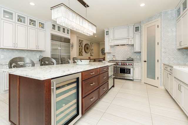 kitchen with high quality appliances, decorative light fixtures, a kitchen bar, a kitchen island, and beverage cooler