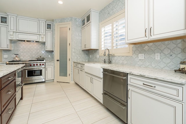 kitchen featuring sink, decorative backsplash, designer range, and light tile patterned floors