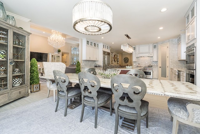 dining space with ornamental molding, light hardwood / wood-style flooring, and a chandelier