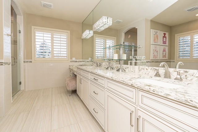 bathroom with tile patterned flooring, vanity, tile walls, a healthy amount of sunlight, and a shower with shower door