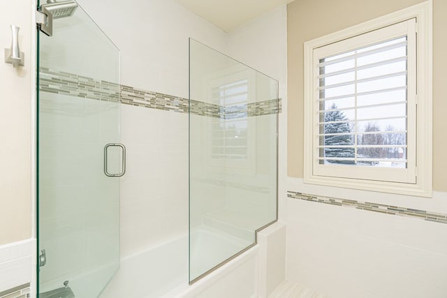 bathroom with combined bath / shower with glass door and tile walls