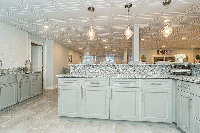 kitchen with hanging light fixtures and light stone countertops