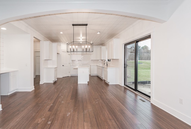 unfurnished living room featuring sink, dark wood-type flooring, and a notable chandelier