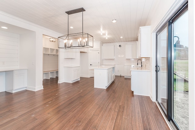 kitchen featuring tasteful backsplash, decorative light fixtures, a kitchen island, white cabinetry, and wood ceiling