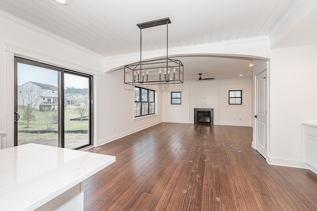 unfurnished living room featuring wooden ceiling, dark wood-type flooring, ceiling fan with notable chandelier, crown molding, and a fireplace