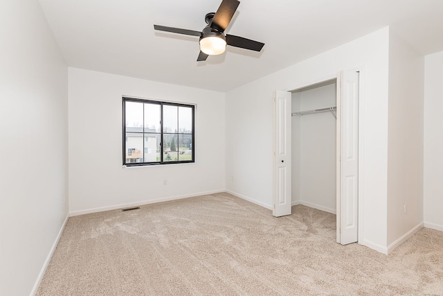 unfurnished bedroom with ceiling fan, light colored carpet, and a closet