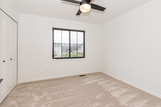 unfurnished bedroom featuring ceiling fan, light carpet, and a closet